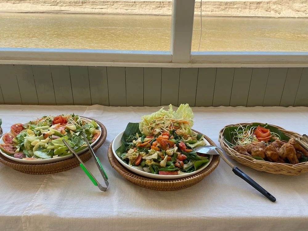 Lunch buffet on board: salads, stir-fried vegetables and fried chicken by a window over the Mekong