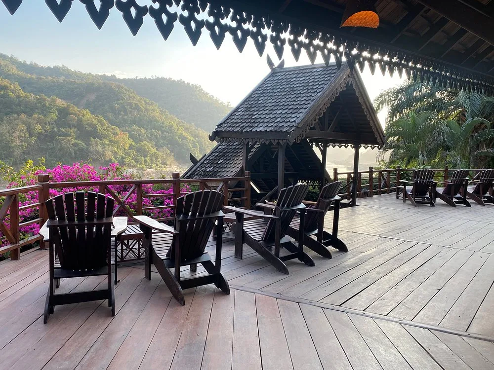 Wooden deck chairs on the Luang Say Lodge terrace, bougainvillea and the forested Mekong valley behind