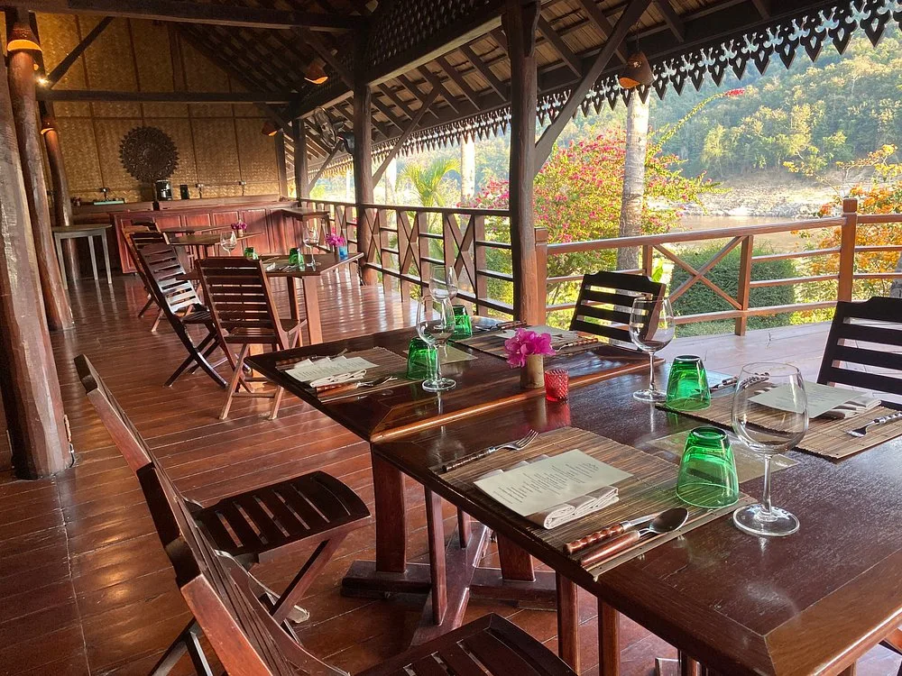 Tables set for dinner on the Luang Say Lodge restaurant terrace above the Mekong