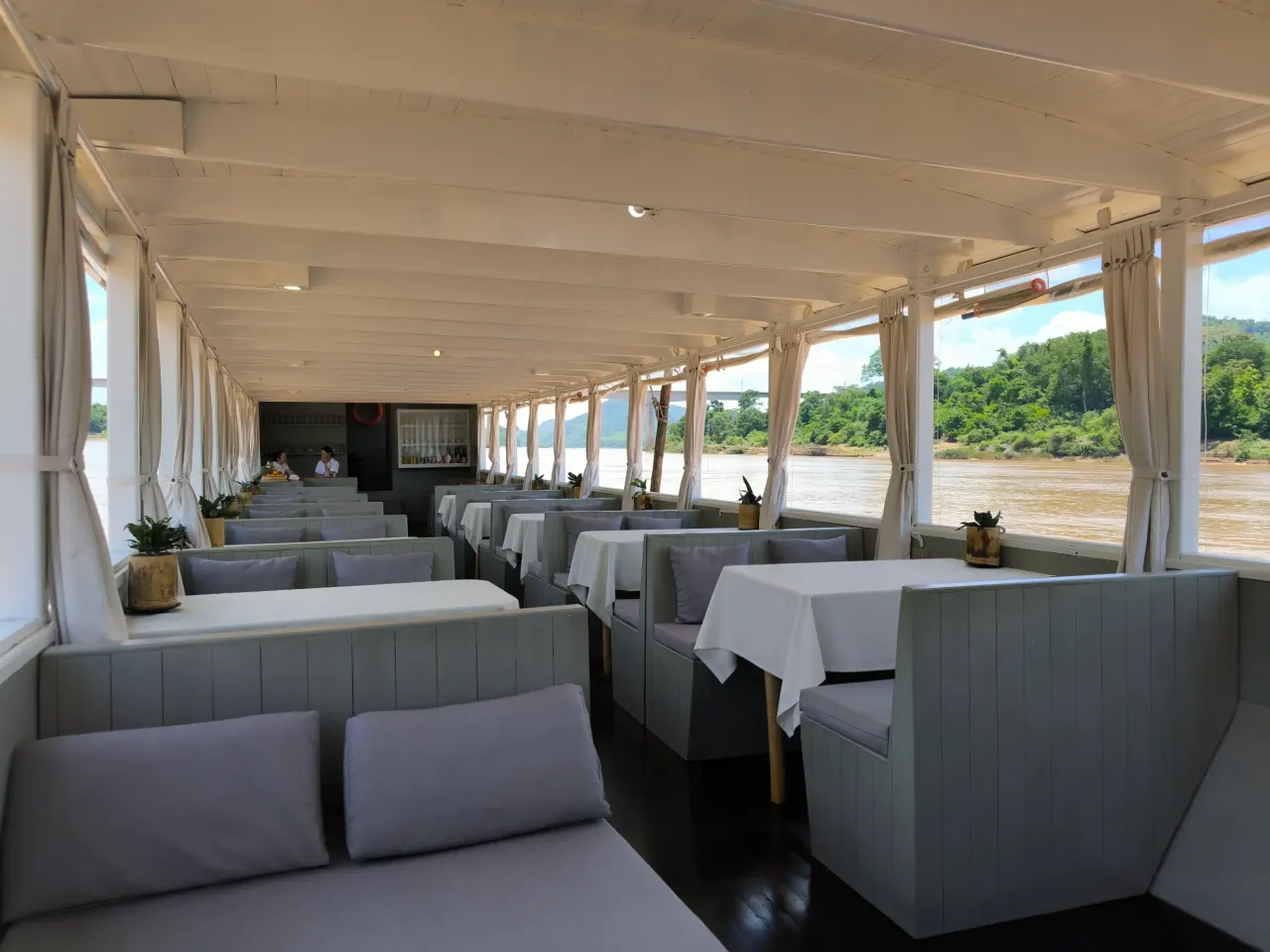 Main deck of the Mekong Cruises boat with lounge seating and panoramic windows on the Mekong River