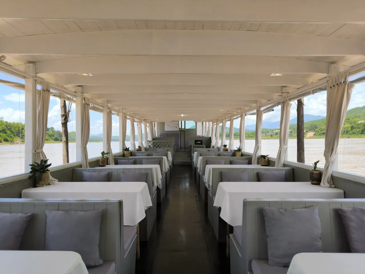 Interior of a traditional Mekong river cruise boat in Laos, tables set for lunch